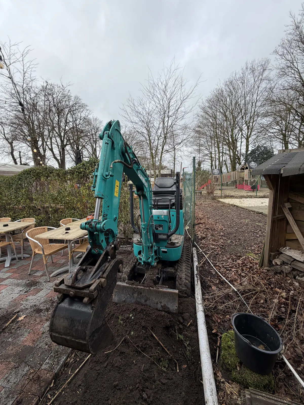 Minigraver die de tuin voorbereidt voor een volledige heraanleg