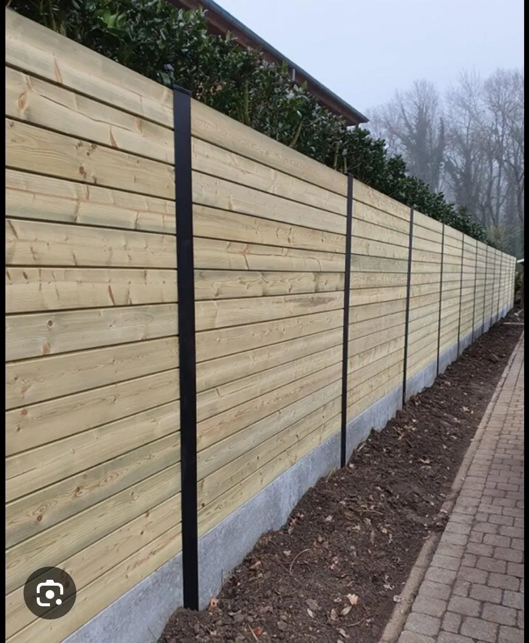 Houten omheining met betonpalen geplaatst langs een tuinpad in West-Vlaanderen