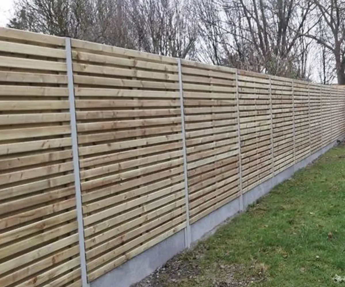 Dubbelzijdige houten omheining met betonpalen langs een tuinrand