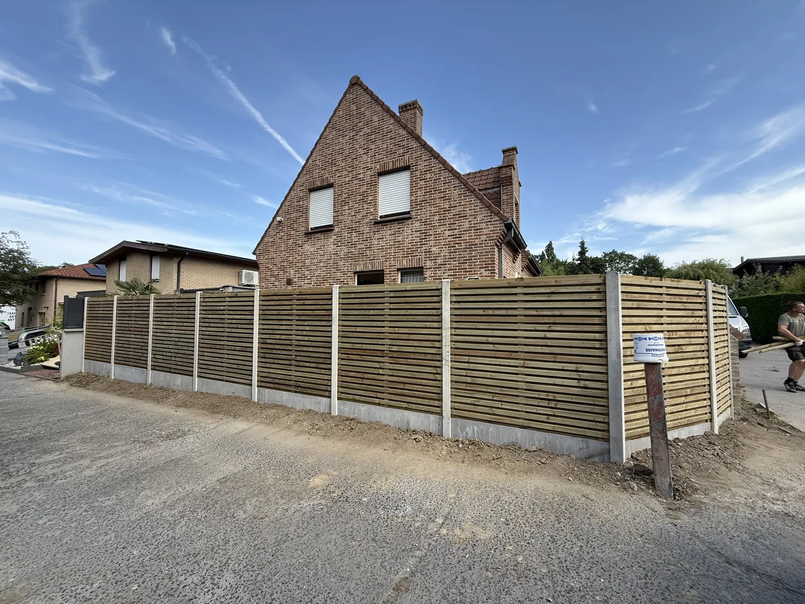 Houten omheining met betonpalen aan de straatzijde van een woning